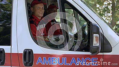 Friendly doctors in ambulance looking at camera, professional emergency service Stock Photo