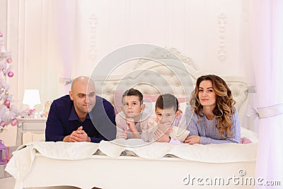 Friendly family chats lying on bed, mom and dad with their child Stock Photo