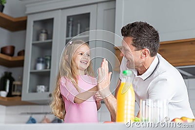 A friendly family from father with daughter stand and manage in the kitchen. A young serious man dad gives his child Stock Photo