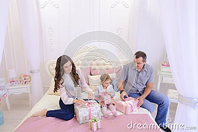 Friendly family in festive mood to exchange gifts sitting on bed Stock Photo