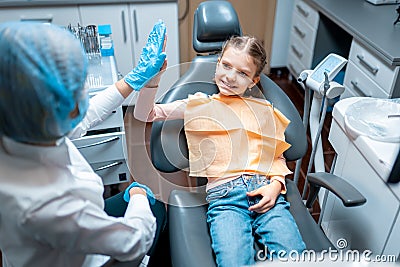 Friendly female dentist giving high five little patient sitting on dental chair after examination Stock Photo