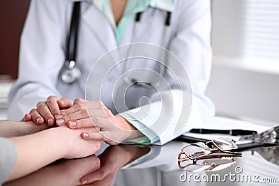 Friendly female doctor hands holding patient hand sitting at the desk for encouragement, empathy, cheering and support Stock Photo