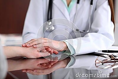 Friendly female doctor hands holding patient hand sitting at the desk for encouragement, empathy, cheering and support Stock Photo