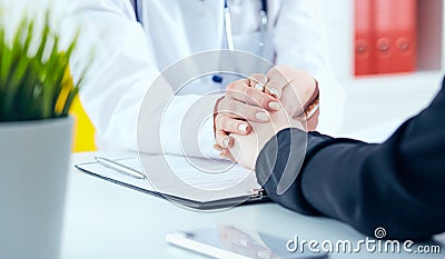 Friendly female doctor`s hands holding female patient`s hand for encouragement and empathy close-up. Partnership, trust Stock Photo