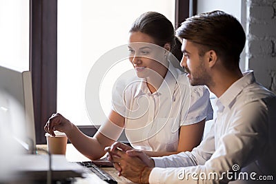 Friendly female mentor training male employee with computer Stock Photo
