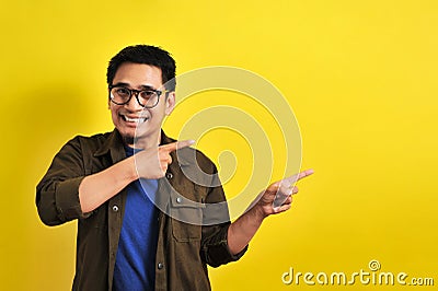 Friendly-looking lively pleasant Asian male with casual t-shirt smiling delighted look at copy space joyful. Self-assured pointing Stock Photo