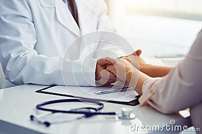 Friendly male doctor reassuring the patient and holding his hands Stock Photo