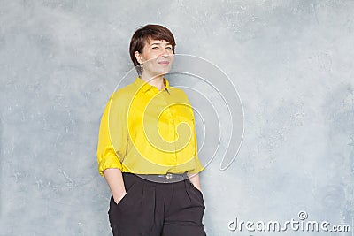 Friendly middle aged business woman in yellow shirt smiling, portrait Stock Photo