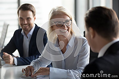 Friendly middle aged female leader laughing at group business meeting Stock Photo