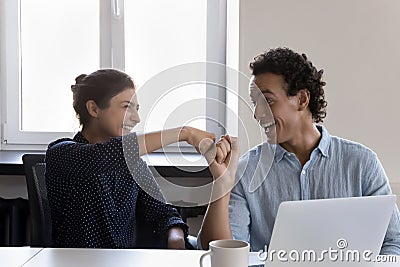 Friendly multiethnic coworkers fist bumping celebrate good teamwork result Stock Photo