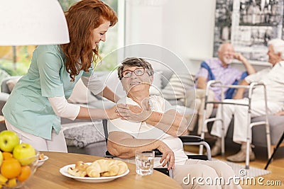 Friendly nurse supporting smiling senior woman in nursing house. Stock Photo