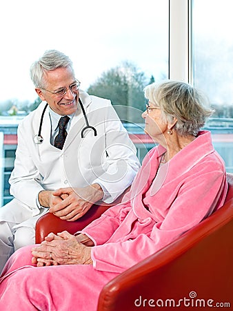 Friendly senior male doctor chatting to a patient. Stock Photo