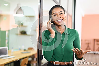 Friendly smiling african-american female employee has pleasant phone conversation Stock Photo