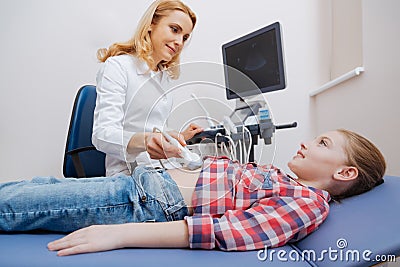 Friendly sonographer providing ultrasound abdomen examination at work Stock Photo