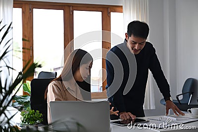 Friendly asian manager explaining reasons and giving advices to new employee. Stock Photo