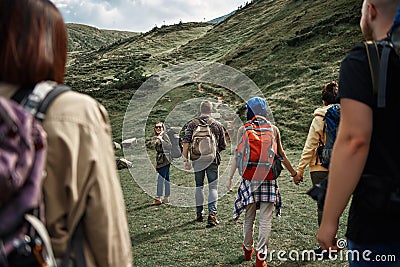 Friendly young backpackers are climbing mountain together Stock Photo