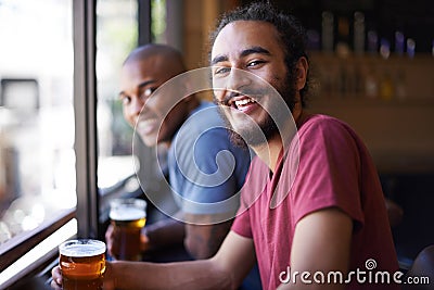 Friends, beer and chill in portrait, smile and relax indoor for fun and bonding in summer to destress. Male people, pub Stock Photo
