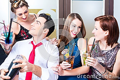 Friends celebrating with barkeeper in cocktail bar Stock Photo