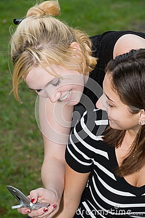 Friends on Cell Phone together (Beautiful Young Blonde and Brunette Girls) Stock Photo