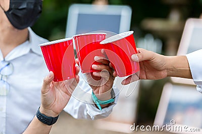 Friends clinking glass on alcohol on party. Friends relaxing with red cups of alcohol. celebration, friendship. Three friends havi Stock Photo