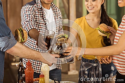 Friends clinking with glasses of cola at picnic on patio Stock Photo