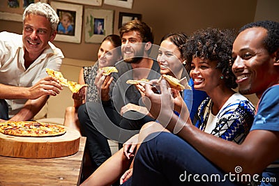 Friends eating pizza at a house party, watching television Stock Photo