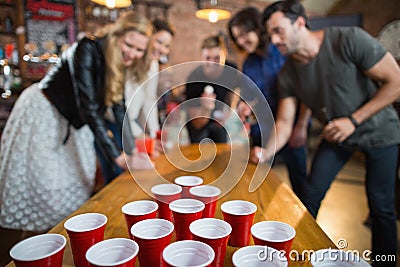 Friends enjoying beer pong game in bar Stock Photo