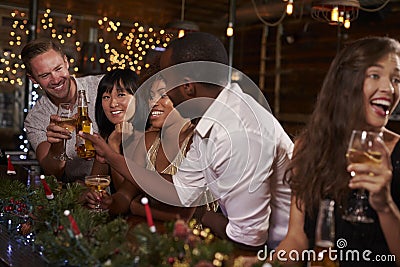 Friends enjoying a Christmas party at a bar making a toast Stock Photo