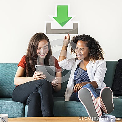 Friends gossiping together on the sofa busy with tablet and holding technology icon Stock Photo