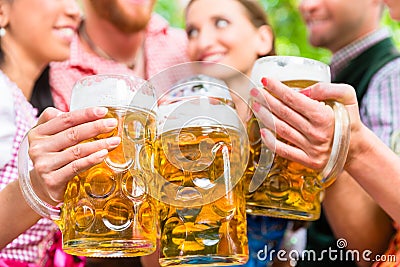 Friends having fun in beer garden while clinking glasses Stock Photo