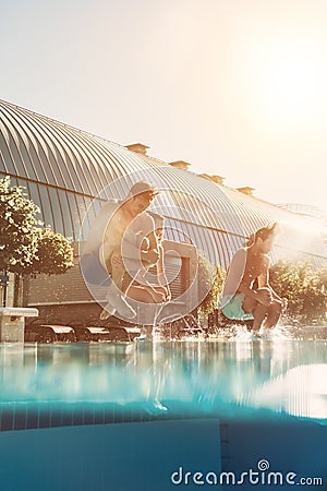 Friends jumping into swimming pool Stock Photo