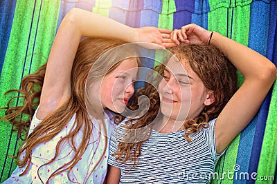 Friends are laughing on a hammock on a hot sunny day Stock Photo