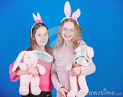 Friends little girls with bunny ears celebrate Easter. Children with bunny toys on blue background. Sisters smiling cute Stock Photo