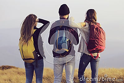Friends of man with two pretty sexy cute girls or women standing with colorful backpacks a on mountain top. Stock Photo