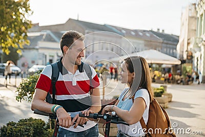 Friends meet while riding electric scooters and have happy conversation Stock Photo