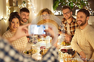 Friends photographing at christmas dinner party Stock Photo