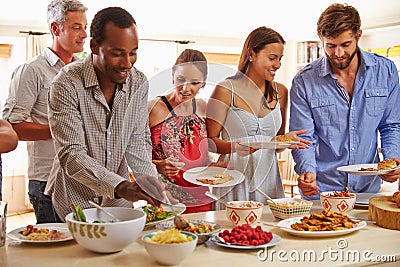 Friends serving themselves food and talking at dinner party Stock Photo