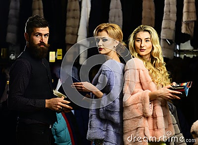 Friends in shop: ladies and gentleman try overcoats on. Stock Photo