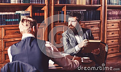 Friends sitting on armchairs in the library, vintage style. Stock Photo