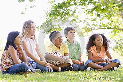 Friends sitting outdoors with soccer ball Stock Photo