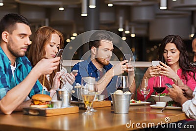 Friends with smartphones dining at restaurant Stock Photo