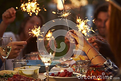 Friends With Sparklers Eating Food And Enjoying Party Stock Photo