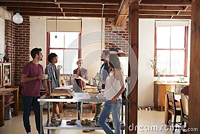 Friends talking over coffee in kitchen, three quarter length Stock Photo
