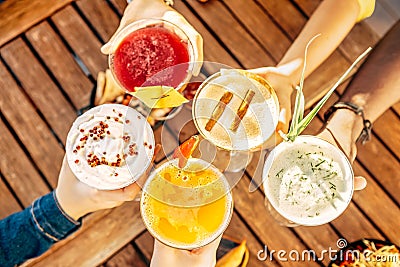 Friends toasting, saying cheers holding tropical fruit cocktails Stock Photo