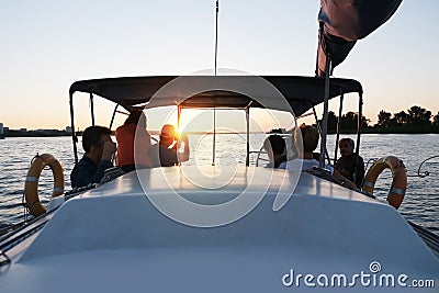 Friends travelling on yacht on calm sunset. Family cruise vacation on a white boat. Evening regatta. People together make yachting Editorial Stock Photo