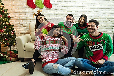 Friends In Ugly Sweater Celebrating Christmas Together At Home Stock Photo