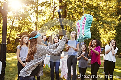 Friends watch teenage girl hitting a piï¿½ata on her birthday Stock Photo