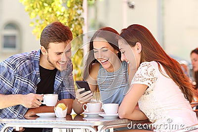 Friends watching media in a smart phone in a coffee shop Stock Photo