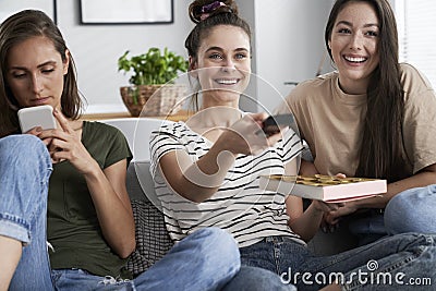 Three friends watching TV with a box of chocolates Stock Photo