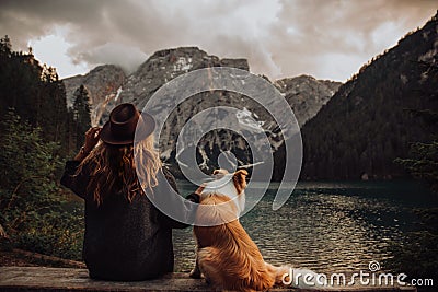 Friendship between child and dog sitting near the lake Lago di Braies Stock Photo